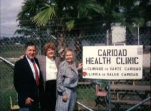 Caridad founders in front of sign