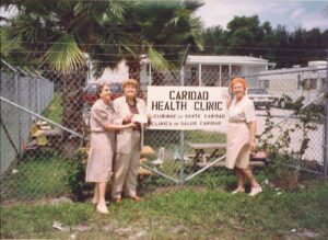 Caridad Health Clinic founders in front of sign