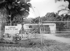 Caridad sign in front of building with a fence